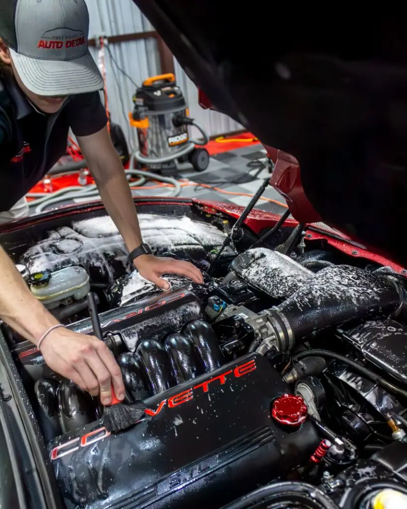 Professional detailing technician cleaning the engine of a Corvette, showcasing expert car care and thorough engine detailing services at Fort Worth Auto Detail